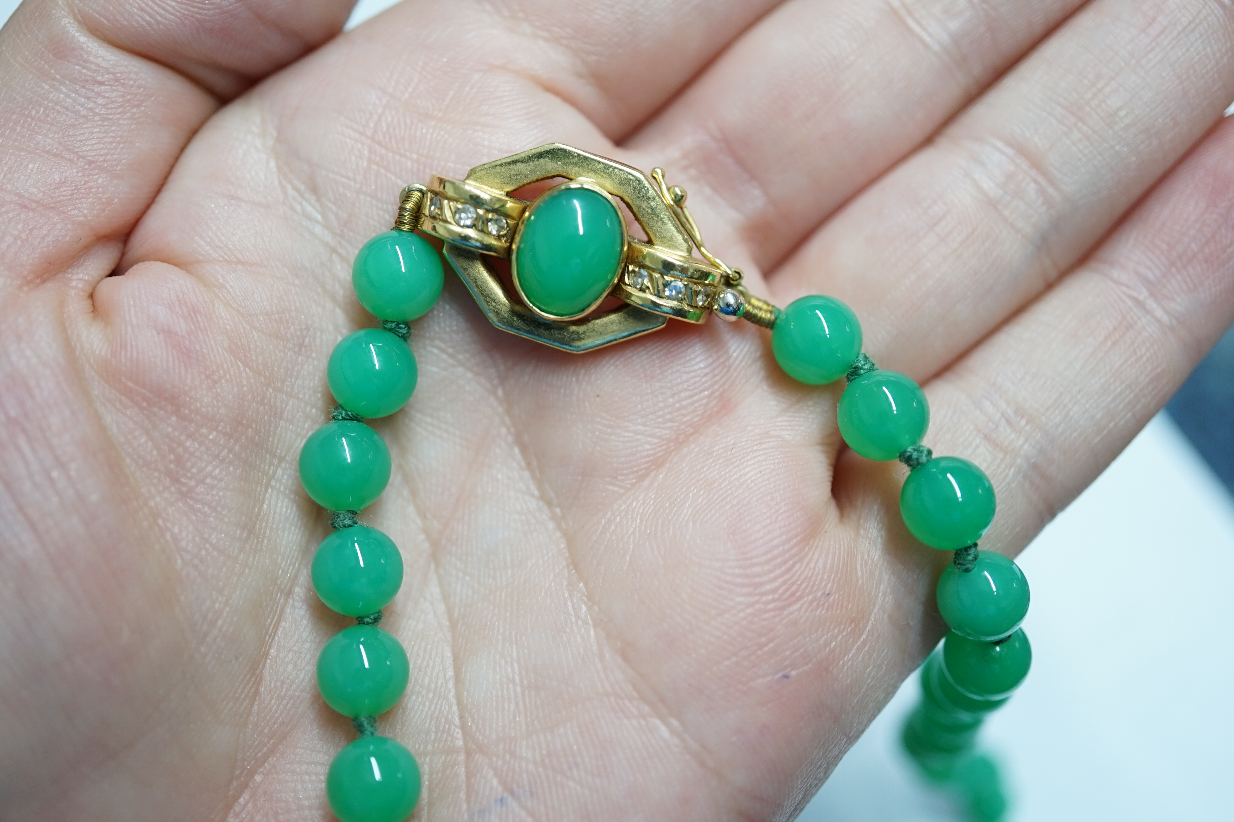 A modern long single strand jadeite bead necklace, with a cabochon jade and diamond chip cluster set 18k clasp